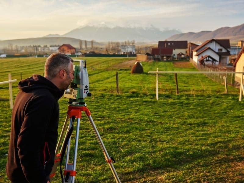 Land surveyor measuring a residential lot before adding a pool, guest house, or detached garage to the property.