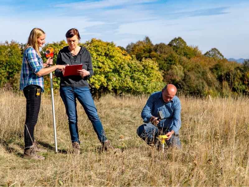 Cadastral surveyor working with a field crew to measure open property for family land division planning in Dallas Texas.